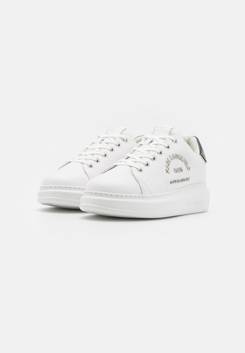 Baskets blanches en cuir avec une texture lisse, bout rond et semelle plateforme épaisse. Comprend des œillets en métal et un logo en relief sur le côté.