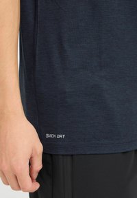 Marine blå hurtig-tørkende atletisk t-skjorte med korte ermer. Har en glatt tekstur, trykt etikett og en tettsittende design, kombinert med sorte shorts.