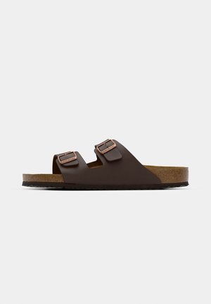 Brown, flat slide sandal with two adjustable straps. Made of a smooth material, featuring a cork footbed and textured rubber sole.
