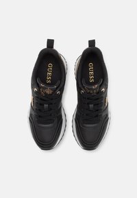Baskets noires en cuir avec des accents dorés. Elles disposent d'une semelle rembourrée, d'un bout rond et d'un système de laçage à l'avant. Le nom de la marque est visible sur la languette.