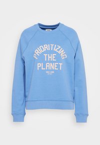 Blå sweatshirt i mjukt tyg, med rundhals och ribbade muddar. Texten lyder "PRIORITIZERA PLANETEN" i persikofärg.