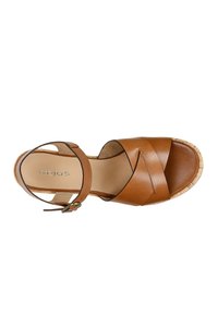 Sandalo in pelle marrone con design incrociato, cinturino alla caviglia con fibbia e suola in sughero. L'interno presenta una fodera liscia di un beige chiaro.
