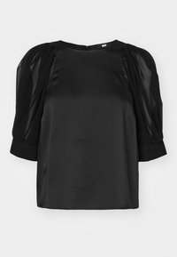 Blouse noire avec des manches courtes bouffantes en tissu transparent et un col rond. Fabriquée en tissu lisse et brillant avec une fermeture éclair au dos.