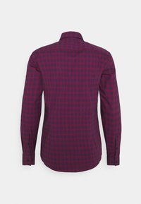 Chemise à manches longues avec un motif à carreaux rouge et bleu marine, présentée de dos sur un fond blanc.