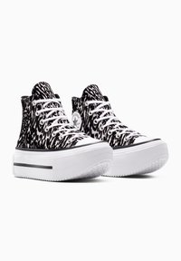Zapatillas altas con un diseño de estampado animal en blanco y negro, cordones blancos y suelas de plataforma blanca gruesas con agarre texturizado.