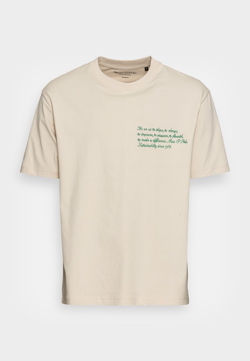 T-shirt en coton beige avec des manches courtes, un col rond et un texte brodé vert en haut à gauche de la poitrine.