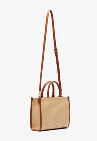 Woven straw handbag with brown leather trim, double handles, and adjustable shoulder strap. Rectangular shape with a flat bottom.