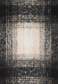 Couverture en laine avec un motif écossais dans des nuances de gris et de crème, dotée d'une texture douce et d'une densité variable dans le design.