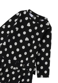 Czarna sukienka w białe kropki i wzory serduszek, z długimi rękawami, okrągłym dekoltem i kokardą w talii. Miękka tekstura materiału.