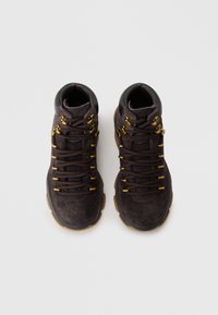 Brown suede high-top sneakers feature gold hardware, round laces, and a textured brown rubber sole. The design is sleek and functional.