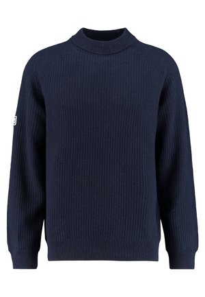 Granatowy sweter wykonany na drutach z prążkowaną fakturą, wysoką okrągłą szyją, długimi rękawami i małą białą naszywką na lewej rękawie.