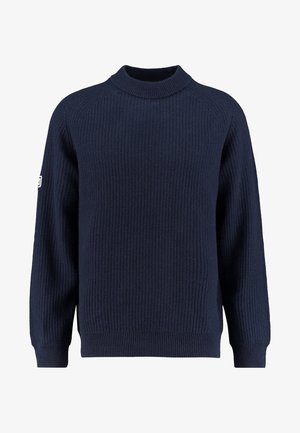 Pull tricoté bleu marine à texture côtelée, col rond haut, manches longues et petit patch blanc sur le bras gauche.