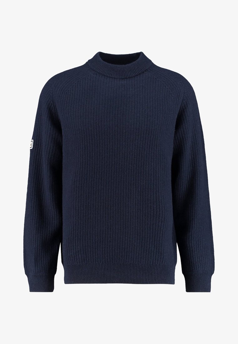 Pull tricoté bleu marine à texture côtelée, col rond haut, manches longues et petit patch blanc sur le bras gauche.