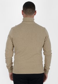 Maglione beige lavorato a maglia con colletto alto a costine e polsini a costine, con dettagli del logo sulla spalla sinistra. Texture liscia.