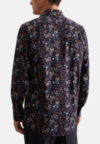 Marineblomstret langærmet skjorte med intrikate mønstre i rød, blå og guld, med traditionel krave og knapmanchetter.