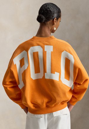 Sweat-shirt orange avec un lettrage surdimensionné "POLO" en blanc dans le dos. Dispose d'un col et de poignets côtelés, fabriqué en coton doux.