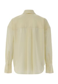 Camicia gialla a maniche lunghe con bottoni, caratterizzata da un motivo testurizzato, con piega sul retro e polsini abbottonati, realizzata in tessuto leggero.