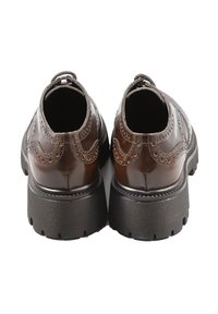 Scarpe in pelle marrone con una finitura lucida, dotate di dettagli brogue e suola nera spessa. La vista posteriore mette in risalto la punta arrotondata e il tacco.