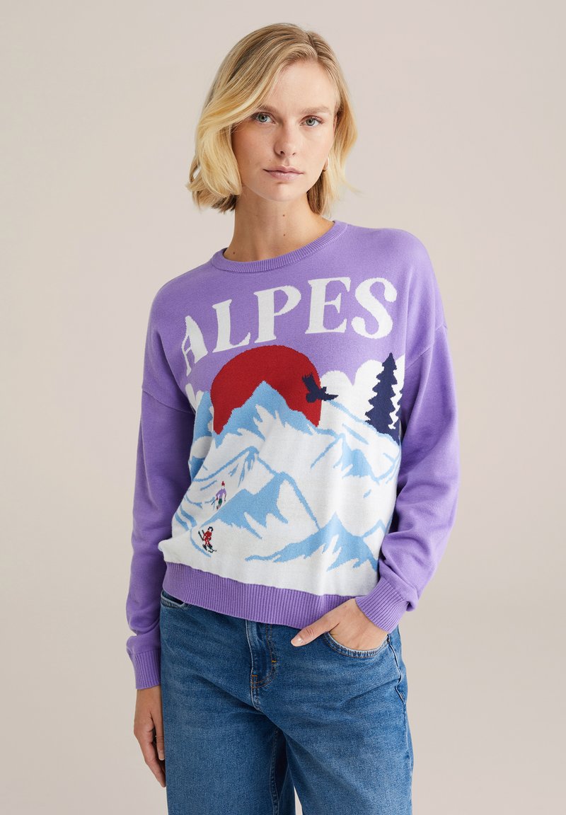 Fialový sveter s nápisom "ALPES", na ktorom sú grafiky hôr a lyžovania v modrej, bielej a červenej farbe. Ríbsový lem a manžety. Voľný strih.
