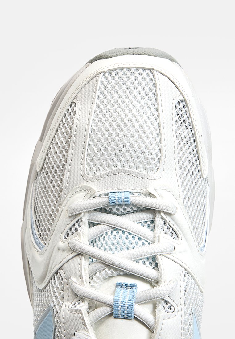 Scarpa atletica bianca in mesh con accenti azzurri, caratterizzata da una parte superiore testurizzata, linguetta imbottita e lacci. Design curvo con area della punta rinforzata.