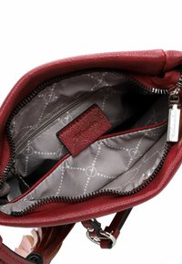 Red leather handbag with a zip closure, featuring a gray patterned interior, a pocket, and silver hardware.