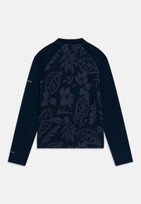 Tumši zila krekla piedurknes ar garām, ar tonālo lapu rakstu uz muguras, izceļot apaļu kakla izgriezumu un raglanu piedurknēm. Zīmola logo uz piedurknēm.