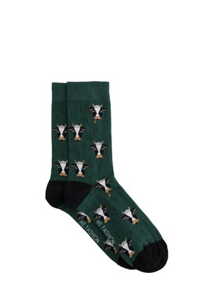 Dark green cotton socks featuring repeated cow face patterns, black accents at the toe and heel, with a ribbed top.