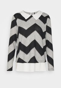 Pull gris à manches longues avec motif zigzag noir, col pointu blanc et couche de tissu blanc à l'ourlet.