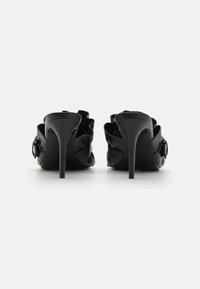 Sapatos de salto alto pretos em pele lisa, com um design franzido na parte de trás e um detalhe com fivela na lateral.