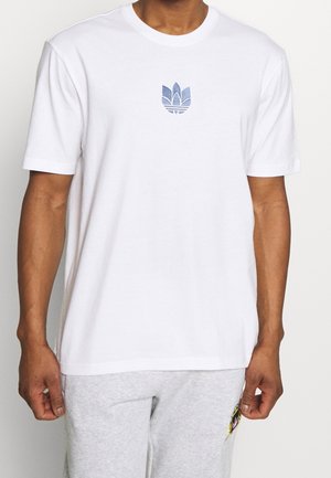 Valkoinen puuvillapaita, jossa on sininen brodeerattu logo rinnassa. Lyhyet hihat, pyöreä kaula-aukko ja rento malli.