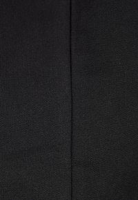 Tessuto nero che mostra una vista ravvicinata della trama a maglia liscia e elastica con fine rigatura e senza cuciture o decorazioni visibili.