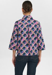 Camicia a fantasia multicolore con un design rosa, blu e verde. Presenta maniche a tre quarti, colletto e una vestibilità rilassata.