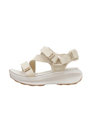 Sándalo deportivo beige con correas ajustables, tejido texturizado, suela gruesa acolchada y suela exterior de goma diseñada para uso casual al aire libre.