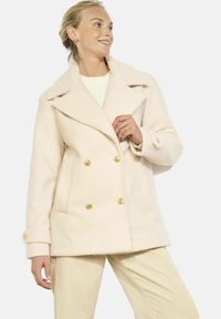 Jasnoróżowy dwurzędowy płaszcz z złotymi guzikami, z klapami i dwoma przednimi kieszeniami, wykonany z teksturowanej, ciepłej tkaniny.