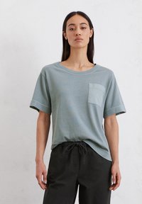 Lichtblauw katoenen T-shirt met korte mouwen, ronde hals en een borstzakje aan de linkerkant, gecombineerd met zwarte broek met trekkoord.