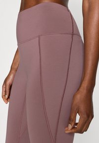 Mauve leggings met een hoge taille, gemaakt van rekbare stof, voorzien van flatlocknaden en een gladde textuur met een aansluitend ontwerp.