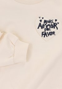 Beige sweatshirt met geribde halslijn en manchetten. Voorzien van een grote hartapplicatie met de tekst "More Amor por Favor" in zwarte letters.