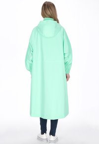 Menta zöld esőkabát kapucnival, hosszú ujjakkal és kényelmes szabással, sima, fényes felülettel, kiemelkedő díszítések vagy kiegészítők nélkül.