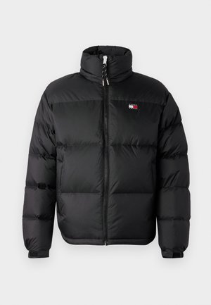 Svart puffjakke med høy krage, frontlukking med glidelås, og horisontale kvilte seksjoner. Har en liten logo på brystet.