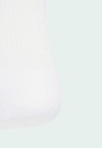 Sock de algodón blanco con textura acanalada, costura en la punta suave y diseño sin costuras. La tela parece elástica y transpirable.