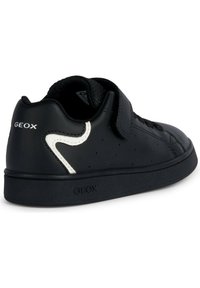 Sneaker in pelle nera con superficie testurizzata, dettagli bianchi e perforazioni. Presenta una striscia con chiusura a strappo e suola in gomma.