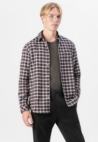 Button-up plaid shirt in dark maroon, white, and grey check pattern. Lightweight fabric, relaxed fit, single chest pocket, paired with black trousers.