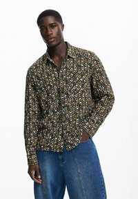 Musthärga särk musta, rohelise ja oranži lillemustriga; pikkade varrukatega, kraega disain, valmistatud sujuvast kangast ja vabast lõiked.