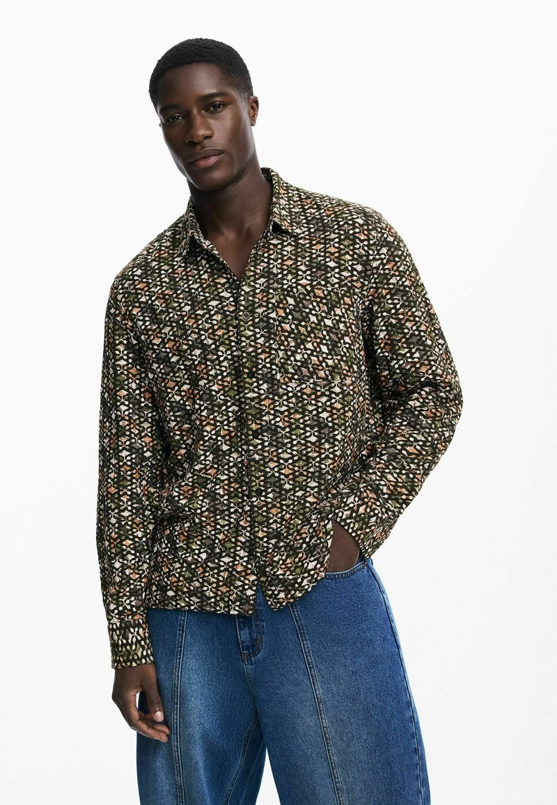 Musthärga särk musta, rohelise ja oranži lillemustriga; pikkade varrukatega, kraega disain, valmistatud sujuvast kangast ja vabast lõiked.