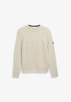 Világos bézs kötött pulóver bordás textúrával, kerek nyakkivágással és hosszú ujjakkal. Színes pöttyökkel díszített, és egy kis fekete címke található az ujjon.