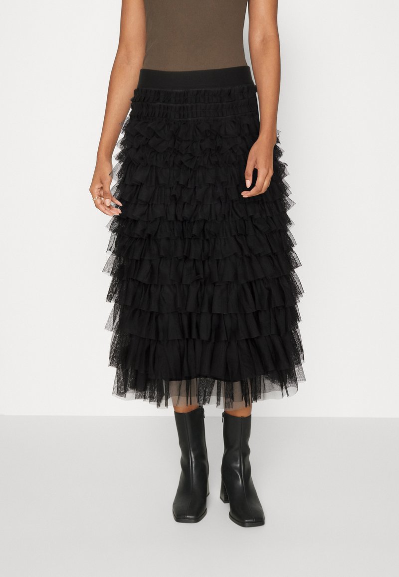 Black tiered tulle skirt with ruffled layers, elastic waistband, and mid-calf length. Paired with sleek black ankle boots.