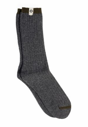 Paire de chaussettes en laine côtelée gris foncé avec des bordures vert olive et une petite étiquette blanche près du haut.