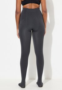 Collant neri opachi a vita alta, con una texture liscia, design senza cuciture, forma aderente e stile senza piedi.