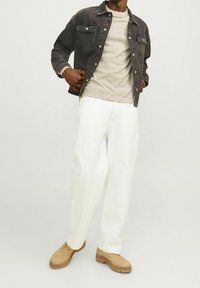 Czarna kurtka dżinsowa z dwoma przednimi kieszeniami, jasnoszary sweter, białe szerokie spodnie oraz beżowe sznurowane buty.