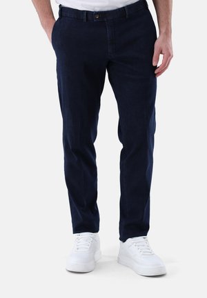 Marineblaue Freizeit-Hosen aus einem weichen Stoff, mit flachem Bund, normalen Taschen und einem Knopfverschluss, kombiniert mit weißen Sneakern.
